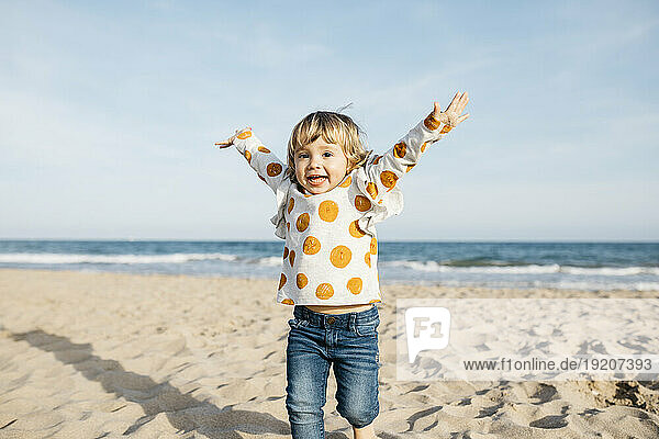 Portrait of happy little girl running on the beach