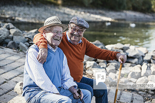 Two old friends sitting by the riverside  having fun