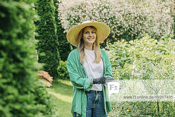 Smiling woman wearing gloves in garden