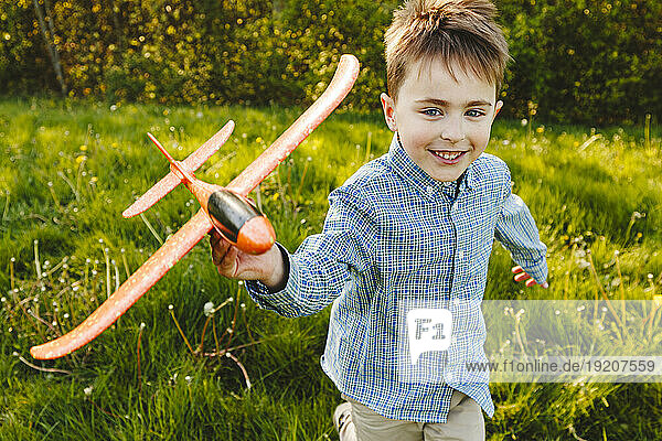 Smiling boy playing with toy airplane in garden