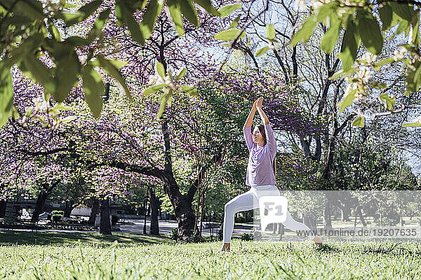 Teenage girl practicing yoga at park in bloom