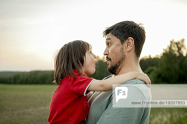 Surprised father carrying son in field
