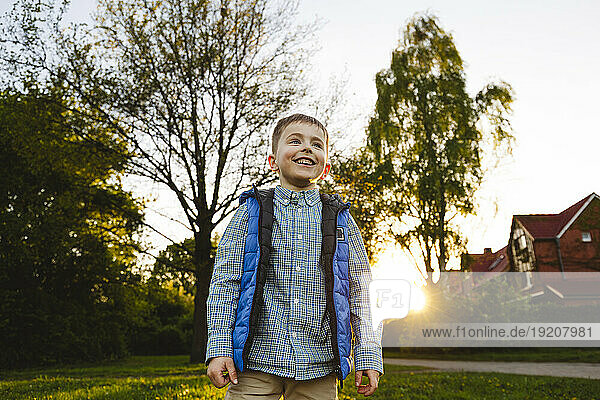 Smiling boy standing in front of house at sunset