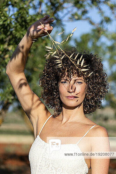 Beautiful woman holding twig at sunny day