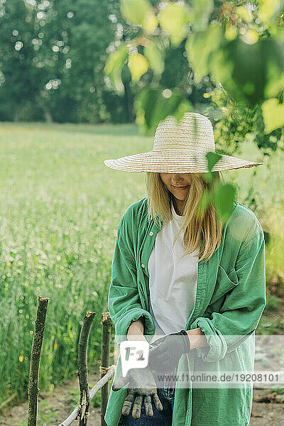 Woman with hat wearing gloves in garden