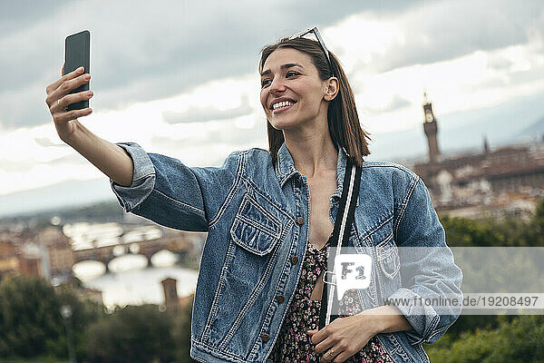 Smiling woman taking selfie in city