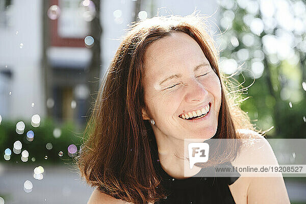 Happy woman laughing with eyes closed at sunny day