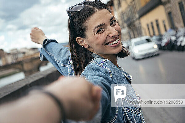 Smiling woman holding partner's hand on street