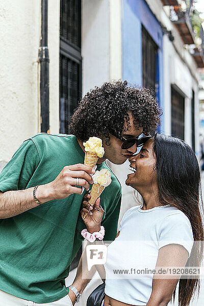 Affectionate couple holding ice cream cone at street