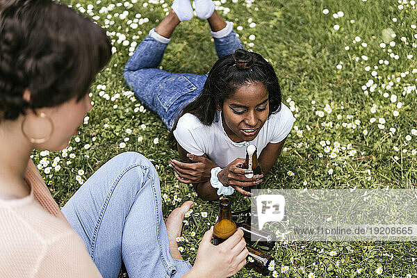 Woman drinking beer with friend at park
