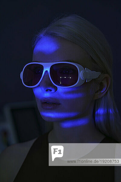 Young woman wearing virtual reality headset with blue neon light