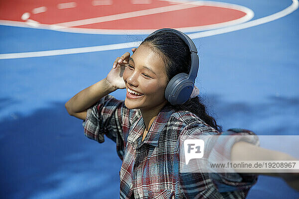 Smiling student listening to music in playground