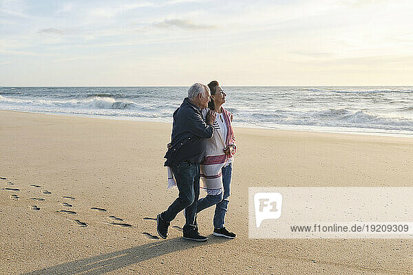 Loving senior couple walking on sand at beach