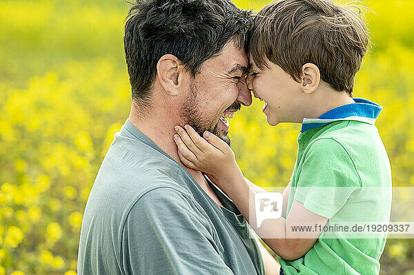 Happy father embracing son at field