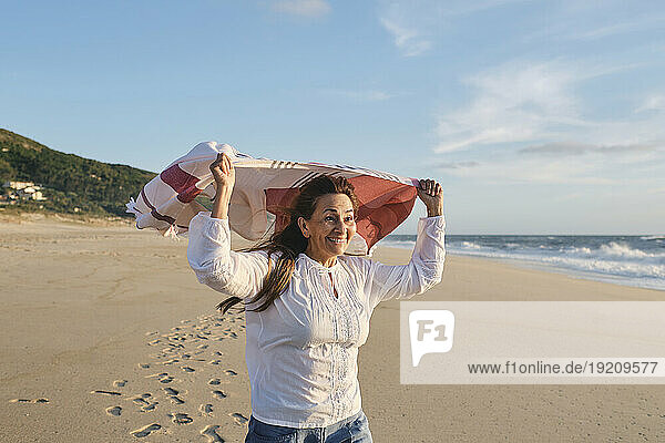 Happy senior woman with scarf at beach