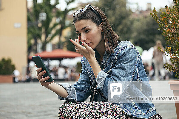 Woman examining eye looking at smart phone