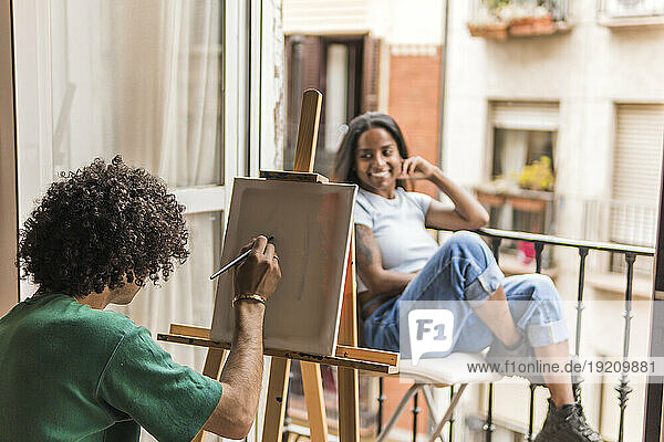 Boyfriend painting on canvas with girlfriend posing at home