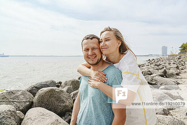 Smiling woman embracing man at beach