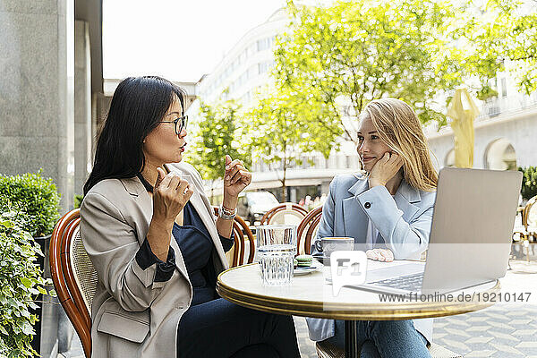 Businesswoman discussing with partner at sidewalk cafe