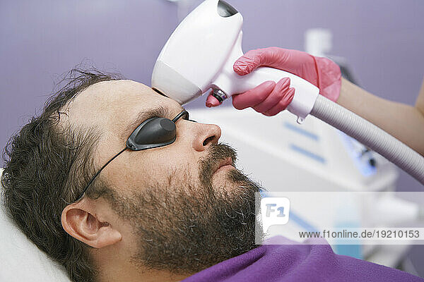 Man with beard getting laser removal treatment at clinic