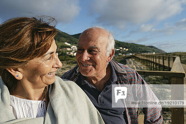 Smiling senior man and woman sitting on sunny day