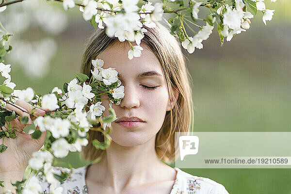 Young woman covering eye with flowers in garden