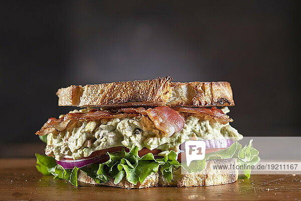 Avocado and egg salad sandwich with bacon  lettuce  tomatoes and red onions