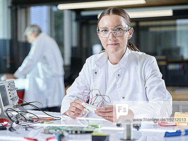 Smiling trainee working over circuit board in laboratory
