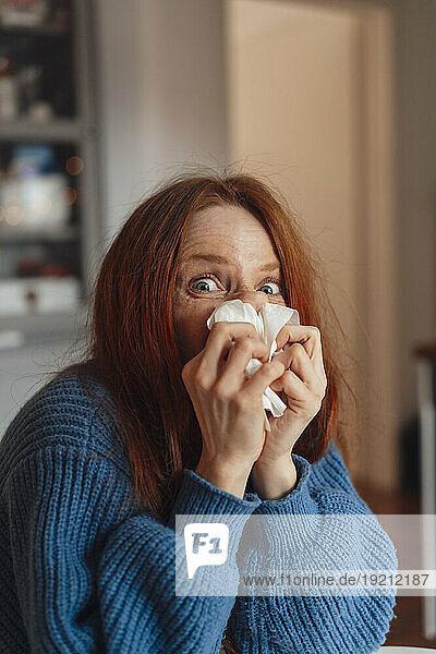 Redhead woman blowing nose on tissue paper