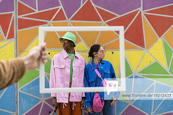 Multiracial couple posing in front of colorful wall