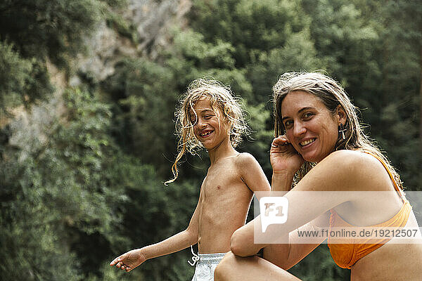 Smiling mother and son spending leisure time in forest