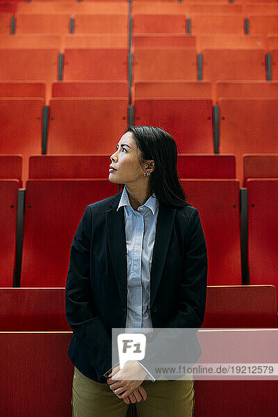 Businesswoman standing in front of red seats at auditorium