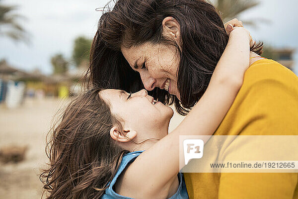 Happy mother embracing and having fun with daughter at beach