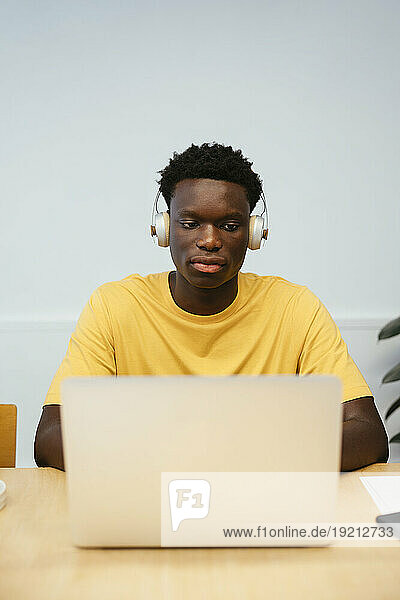 Student wearing wireless headphones using laptop at desk