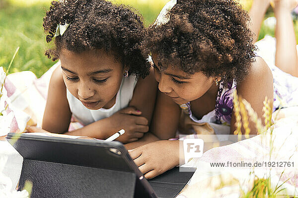 Curious twin sisters using tablet PC in garden