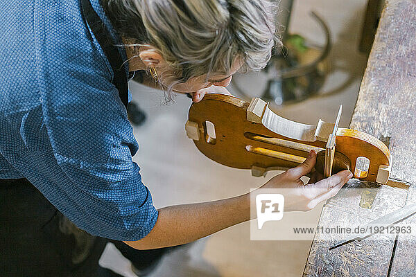 Luthier working on violin at desk in workshop