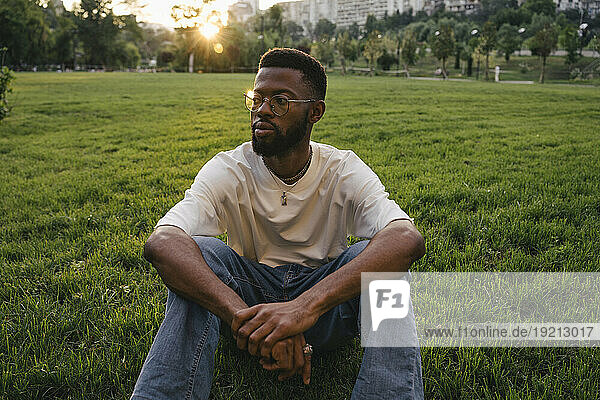 Contemplative man sitting on grass in park