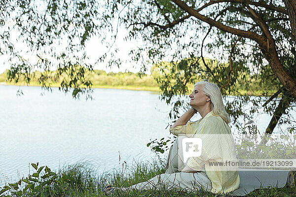 Relaxed woman sitting at lakeshore