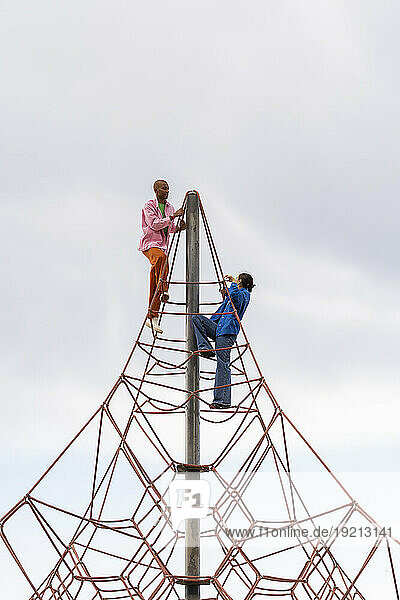 Couple climbing on jungle gym in park