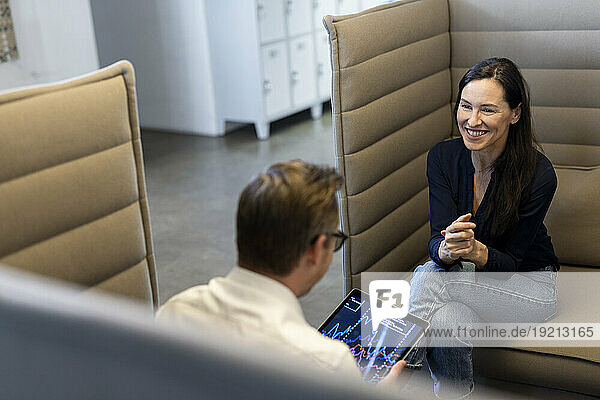 Smiling businesswoman having discussion with colleague in office