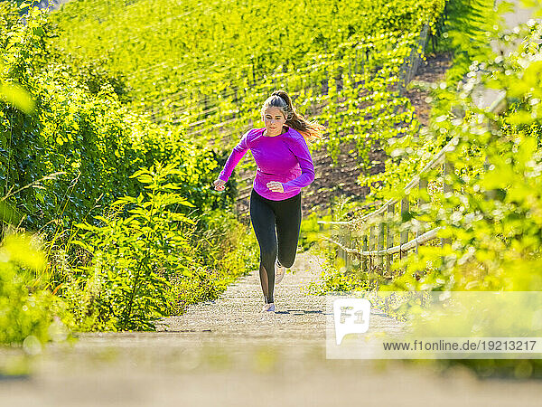 Determined young woman running on steps at vineyard