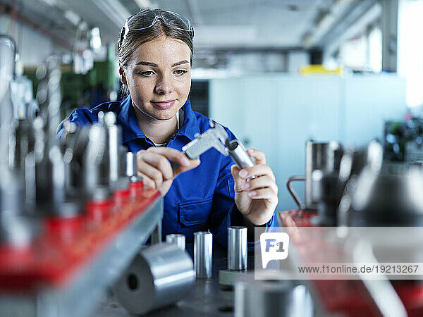Smiling blue-collar worker checking CNC tool in factory