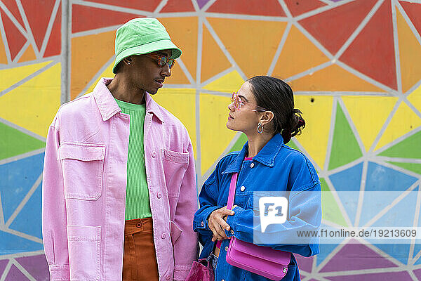 Multiracial couple talking in front of colorful wall