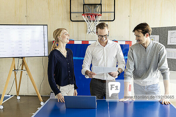 Happy businessman reading document with colleagues in modern office