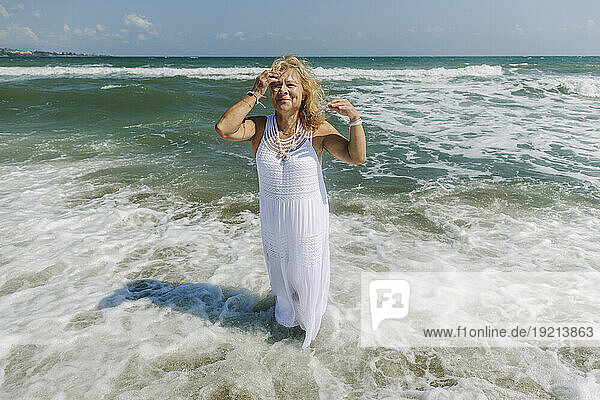 Senior woman wearing dress standing on shore at beach