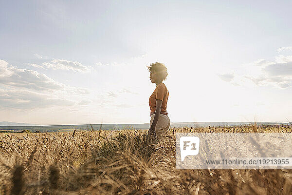 Young woman enjoying solitude in barley field at sunset