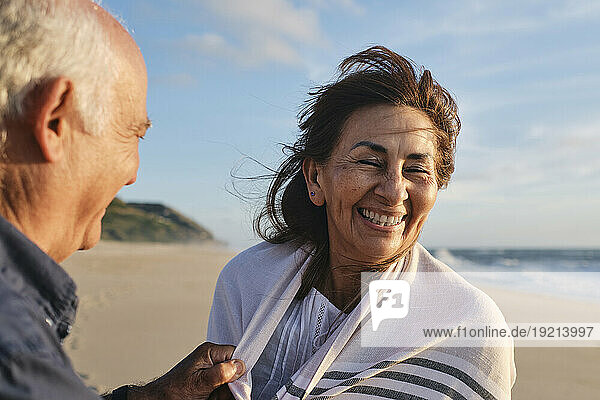 Happy senior woman and man having fun at beach on sunny day