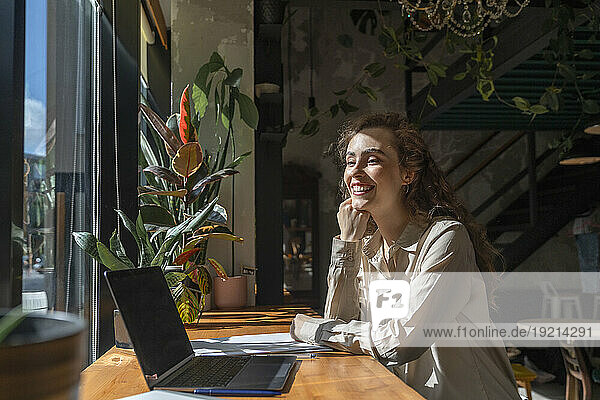 Happy young businesswoman sitting at cafe