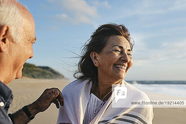 Cheerful senior woman enjoying with man at beach