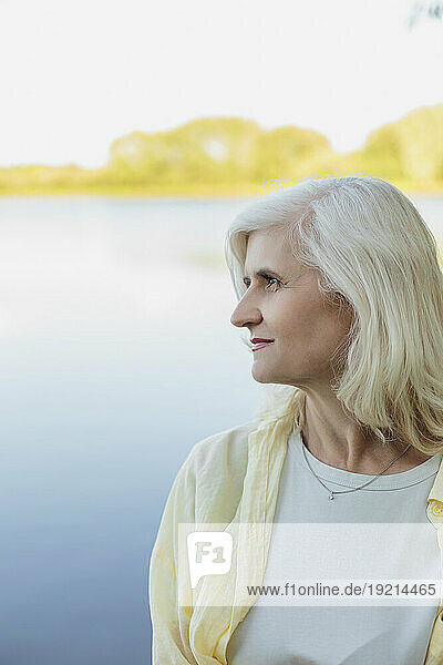 Thoughtful mature woman with grey hair at lake